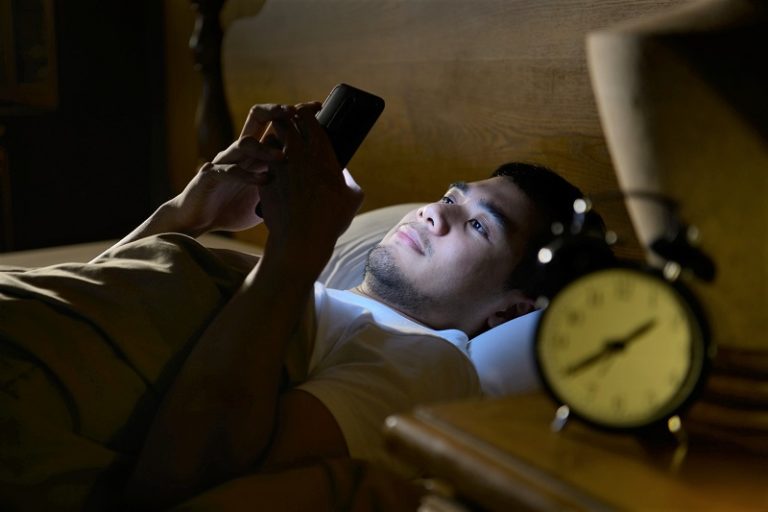 Man looking at a smart phone late at night.