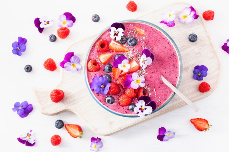 healthy spring berry smoothie bowl with flowers and chia seed