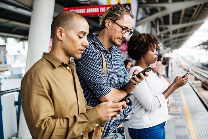 People with a technology addiction may feel compelled to check their smartphone wherever they are, including while waiting for the subway, like this group of people.